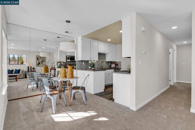 kitchen with sink, carpet floors, white cabinets, pendant lighting, and backsplash