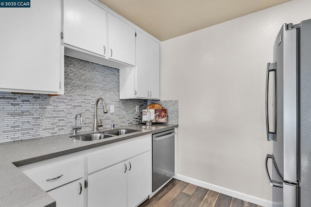 kitchen with sink, appliances with stainless steel finishes, dark hardwood / wood-style flooring, white cabinets, and backsplash