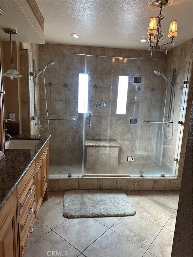 bathroom with tile patterned floors, vanity, a chandelier, and a shower with door