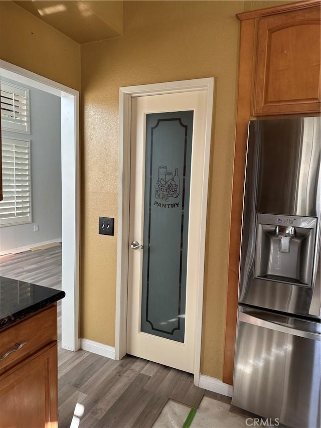 kitchen featuring hardwood / wood-style flooring, dark stone counters, and stainless steel fridge