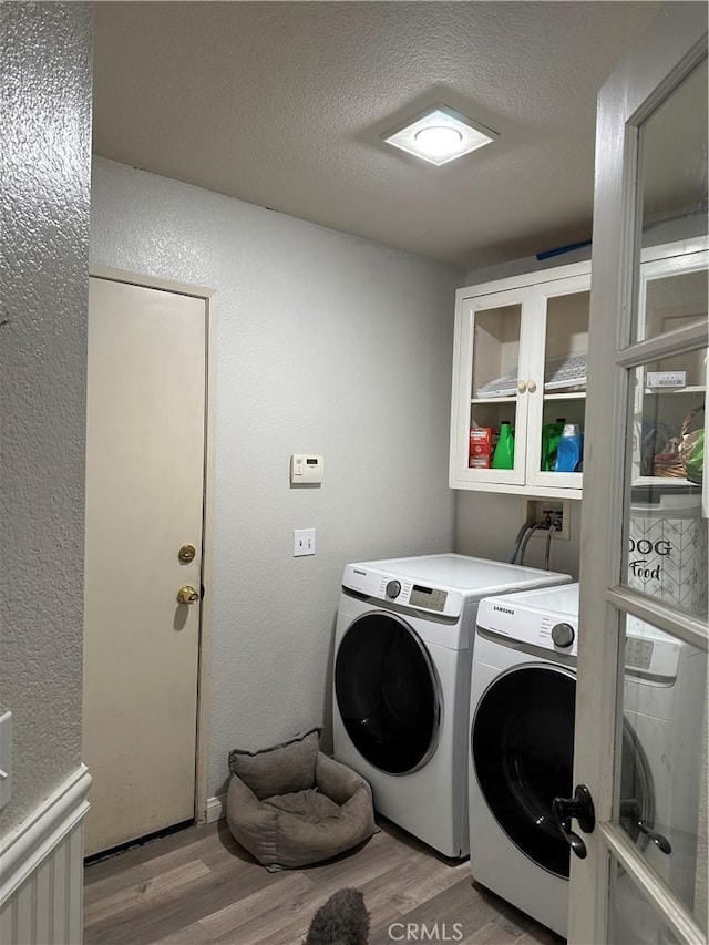 laundry room featuring independent washer and dryer, a textured ceiling, and light wood-type flooring