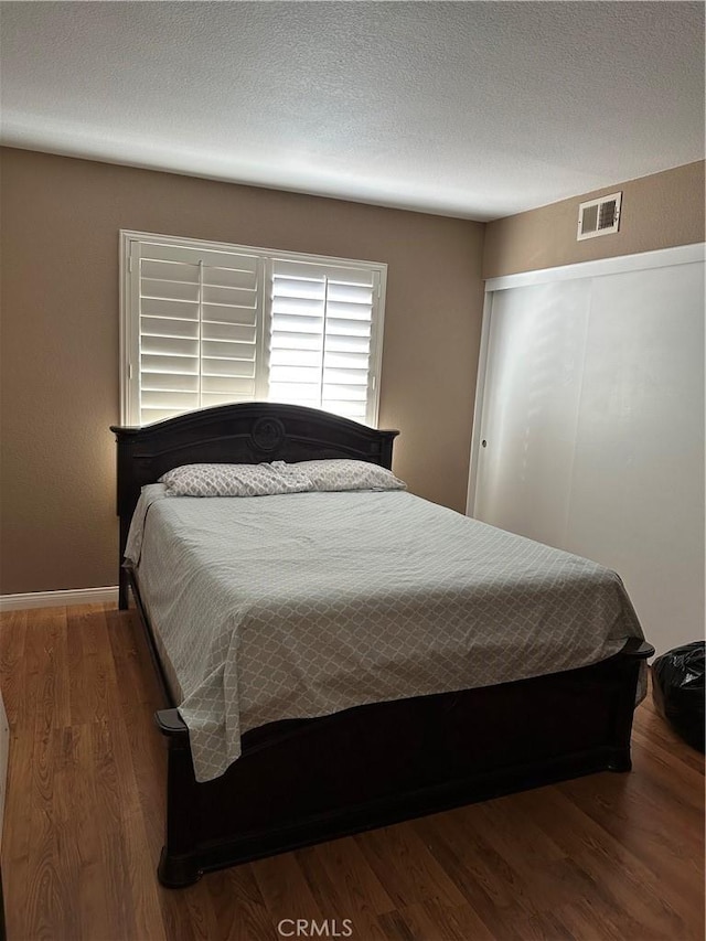 bedroom featuring a textured ceiling and dark hardwood / wood-style flooring