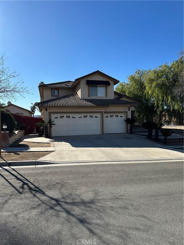 view of front of property featuring a garage, a tile roof, fence, concrete driveway, and stucco siding