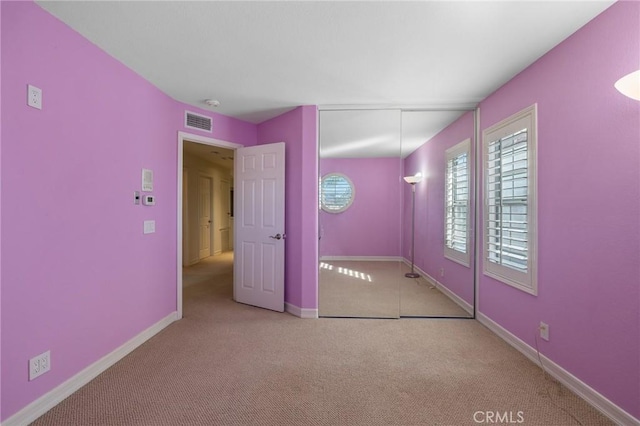 unfurnished bedroom with a closet and light carpet