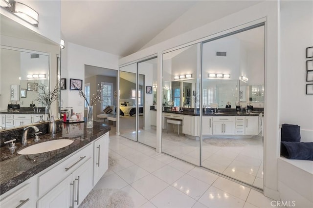 bathroom with lofted ceiling, tile patterned flooring, and vanity