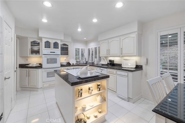 kitchen featuring light tile patterned floors, sink, white cabinetry, double oven, and a center island