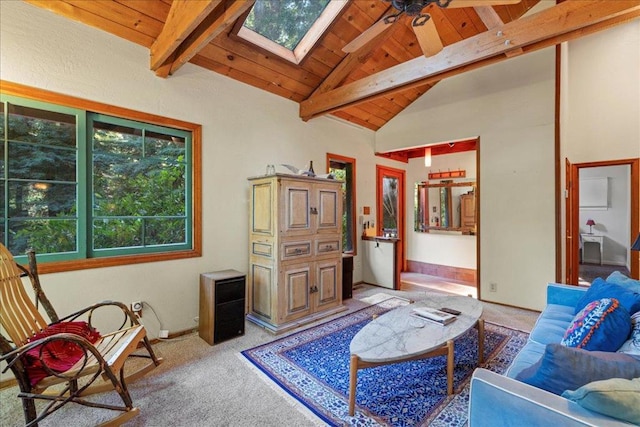 sitting room with a skylight, wooden ceiling, carpet flooring, ceiling fan, and beam ceiling