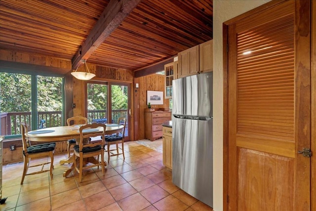 tiled dining area featuring beamed ceiling, wooden walls, and wooden ceiling