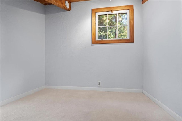 carpeted empty room with beam ceiling