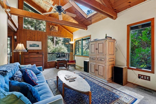 living room featuring lofted ceiling with skylight, light colored carpet, wooden ceiling, wooden walls, and ceiling fan