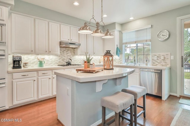 kitchen with hanging light fixtures, plenty of natural light, stainless steel appliances, and white cabinets