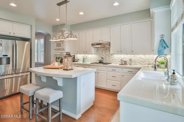 kitchen featuring sink, a center island, pendant lighting, stainless steel appliances, and white cabinets