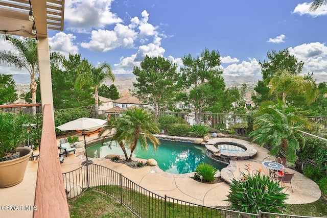 view of swimming pool with a mountain view, a patio area, and an in ground hot tub