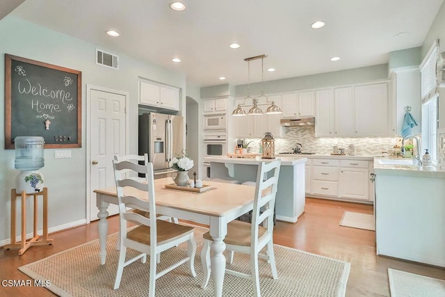 kitchen with pendant lighting, white appliances, sink, and white cabinets