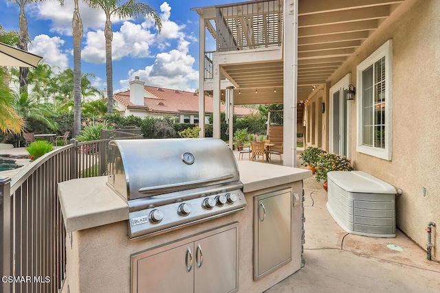 view of patio / terrace with area for grilling, a balcony, and an outdoor kitchen