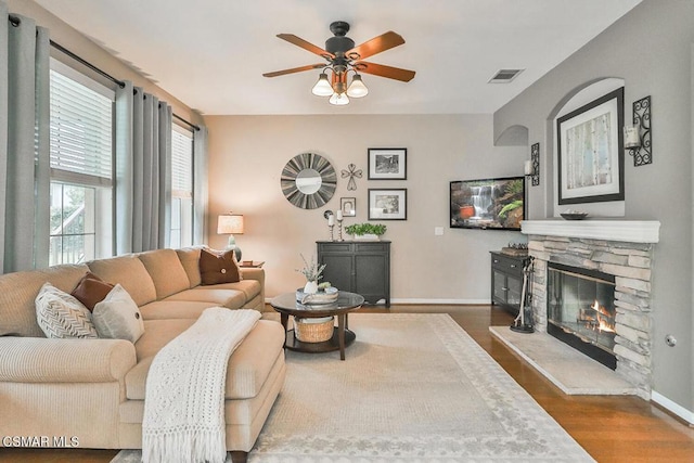 living room featuring dark hardwood / wood-style flooring, a fireplace, and ceiling fan