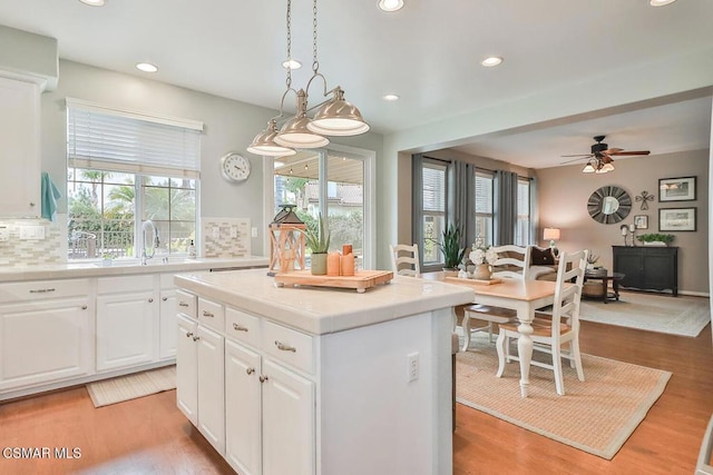 kitchen featuring white cabinetry, a wealth of natural light, a kitchen island, and pendant lighting