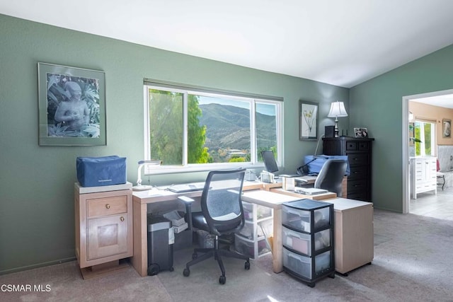 office space with light colored carpet, a mountain view, and vaulted ceiling