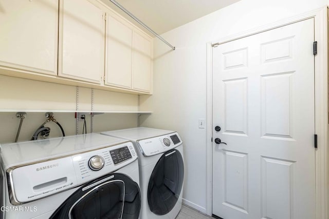 laundry area featuring cabinets, light tile patterned floors, and washer and clothes dryer