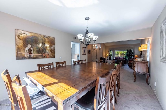 carpeted dining room featuring a notable chandelier