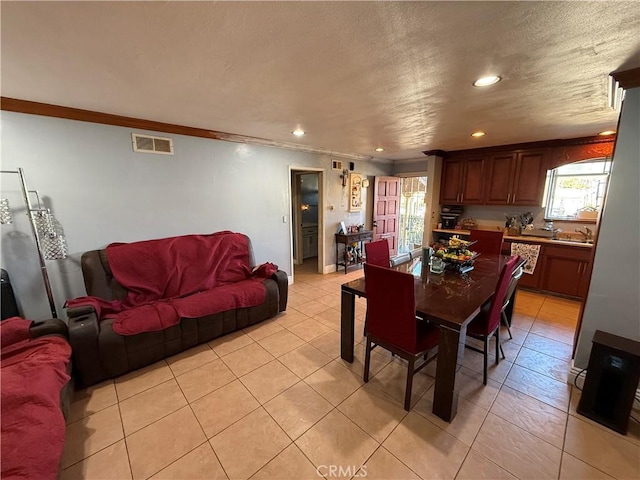 tiled dining area featuring crown molding, sink, and a textured ceiling