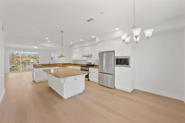 kitchen with stainless steel appliances, a center island, pendant lighting, and white cabinets