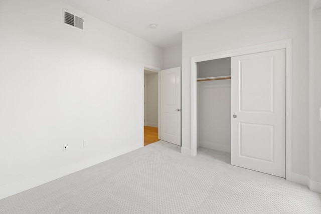 unfurnished bedroom with light colored carpet and a closet