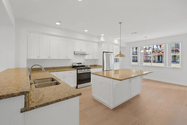 kitchen featuring appliances with stainless steel finishes, pendant lighting, sink, white cabinets, and kitchen peninsula