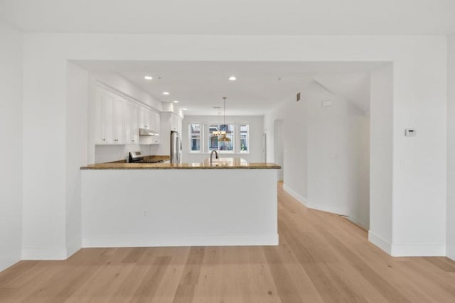 kitchen with pendant lighting, stainless steel fridge, white cabinetry, stove, and kitchen peninsula