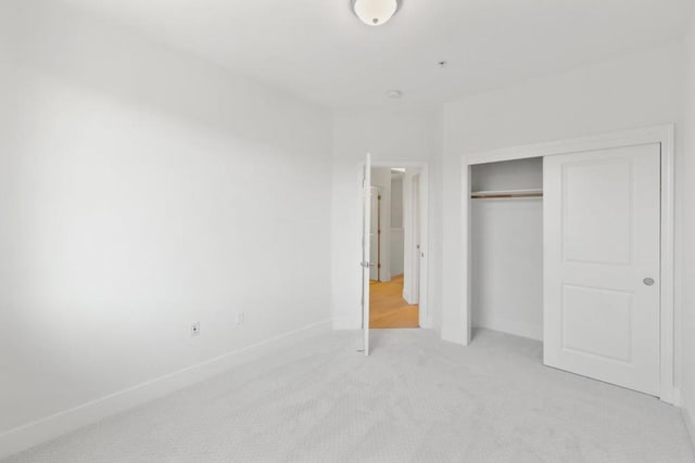 unfurnished bedroom with light colored carpet and a closet