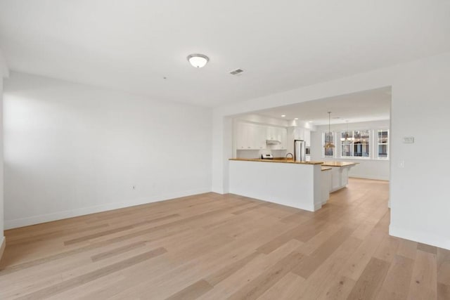 unfurnished living room featuring sink and light hardwood / wood-style flooring