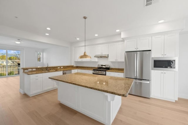 kitchen with pendant lighting, white cabinetry, stainless steel appliances, and kitchen peninsula