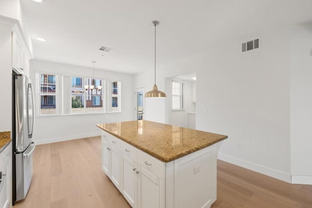 kitchen featuring white cabinetry, stainless steel fridge, a center island, and stone counters