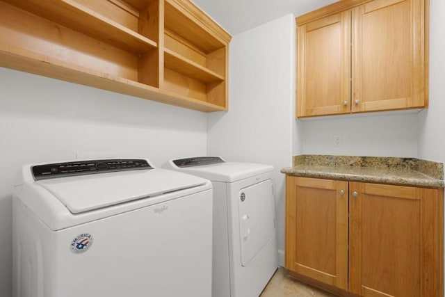 laundry room with washing machine and dryer, cabinets, and light tile patterned flooring