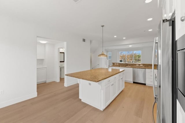 kitchen featuring sink, white cabinetry, hanging light fixtures, a kitchen island, and stainless steel appliances