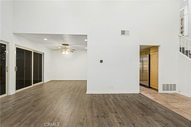 interior space featuring a towering ceiling, hardwood / wood-style floors, and ceiling fan