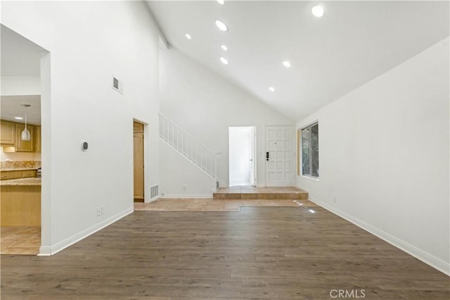 unfurnished living room featuring dark hardwood / wood-style floors and a towering ceiling