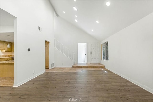 unfurnished living room featuring dark wood-style floors, recessed lighting, visible vents, stairway, and a high ceiling