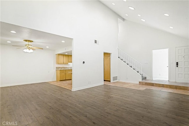 unfurnished living room featuring a ceiling fan, stairway, visible vents, and light wood-style floors