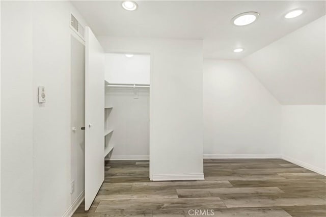 walk in closet with dark wood finished floors, visible vents, and vaulted ceiling