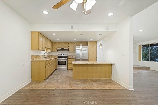 kitchen with sink, appliances with stainless steel finishes, hanging light fixtures, light brown cabinets, and light wood-type flooring