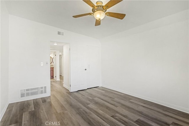 spare room featuring a ceiling fan, baseboards, visible vents, and dark wood-type flooring