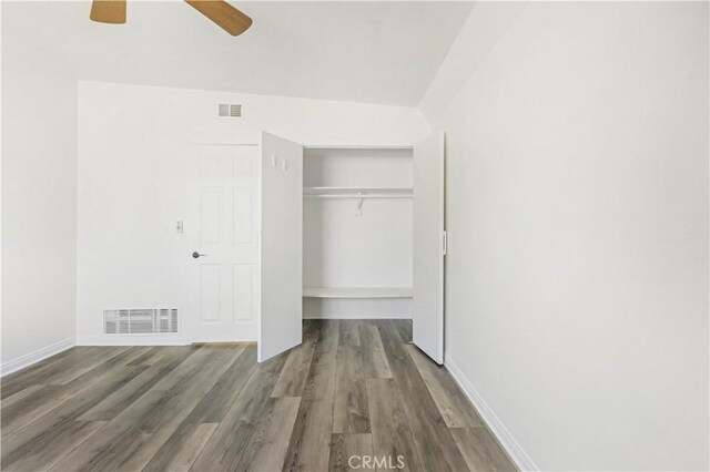 unfurnished bedroom with dark hardwood / wood-style flooring, a closet, and ceiling fan