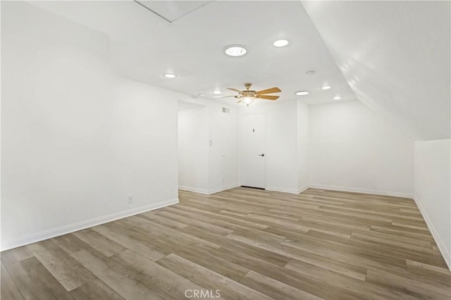 spare room featuring ceiling fan, recessed lighting, baseboards, vaulted ceiling, and light wood finished floors