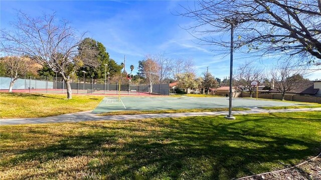 view of community featuring basketball hoop and a lawn