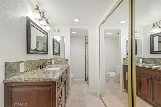 bathroom with toilet, visible vents, two vanities, and a sink