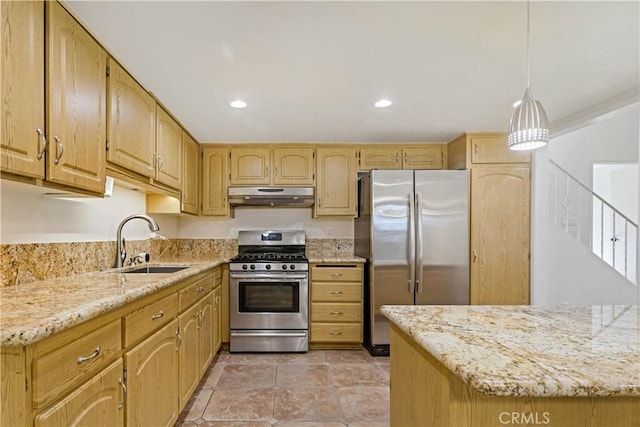 kitchen featuring light stone counters, under cabinet range hood, stainless steel appliances, a sink, and decorative light fixtures