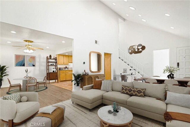 living room with ceiling fan, high vaulted ceiling, and light hardwood / wood-style flooring