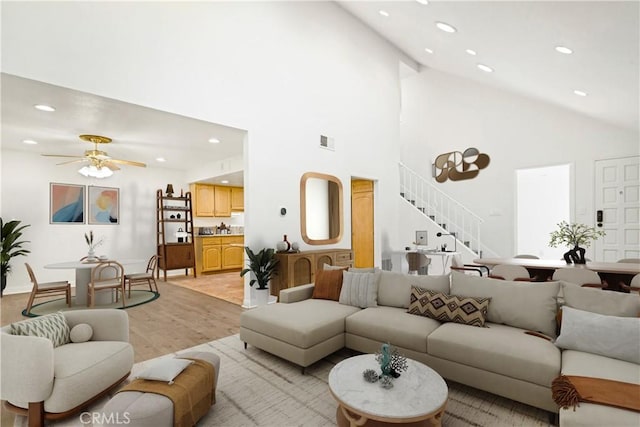 living room with ceiling fan, high vaulted ceiling, and light wood-type flooring