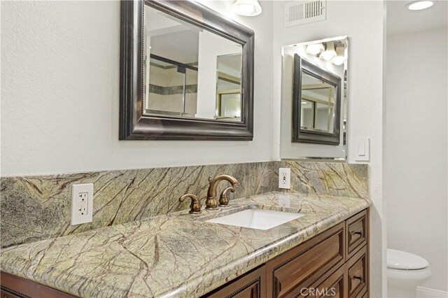 bathroom with vanity, tasteful backsplash, and toilet